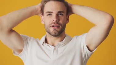 Yakışıklı genç adam sarı duvar arkasında izole edilmiş.