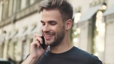 Sokakta cep telefonuyla konuşan genç mutlu bir adam.