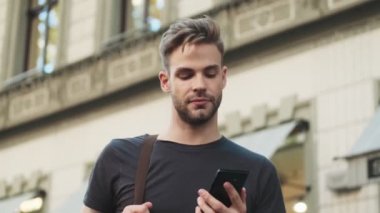 Sokakta cep telefonu kullanan genç bir adam.