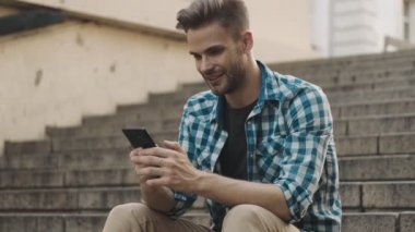 Sokakta cep telefonu kullanan iyimser bir genç.
