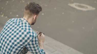 Sokakta cep telefonu kullanan bir adamın arka görüntüsü.
