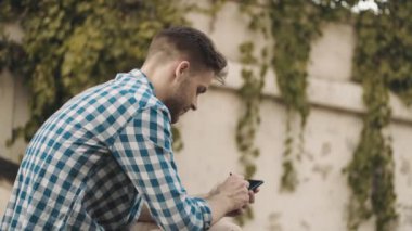 Sokakta cep telefonu kullanan bir adamın yan görüntüsü.