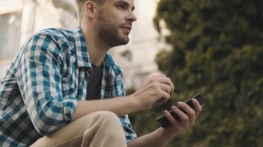 Sokakta cep telefonu kullanan ciddi bir adamın yan görüntüsü.