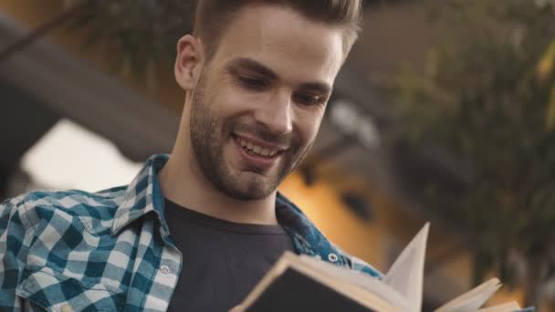 Приятно Оптимистичный Молодой Человек Читающий Книгу Улице — стоковое видео