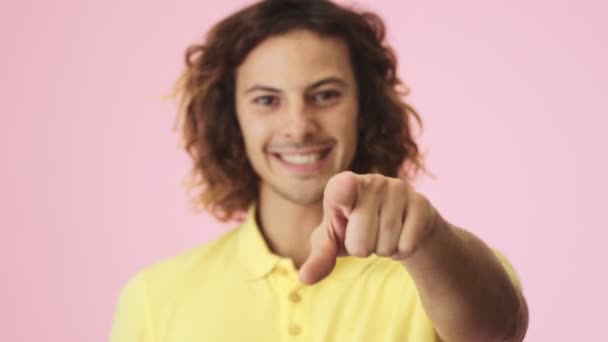 Gülümseyen Kıvırcık Bir Gencin Yakın Çekim Görüntüsü Izleyiciyi Işaret Ediyor — Stok video