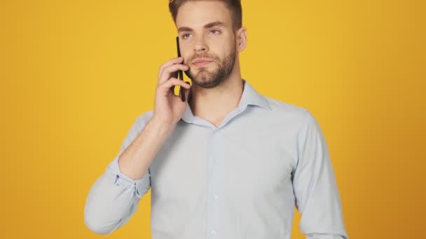 Jovem Sério Está Falando Seu Smartphone Isolado Sobre Fundo Amarelo — Vídeo de Stock