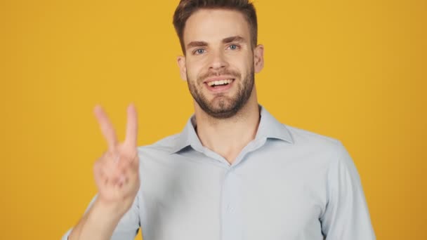 Memnun Genç Bir Adam Barış Işareti Gösteriyor Stüdyoda Sarı Bir — Stok video