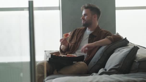 Привлекательный Молодой Человек Ест Пиццу Сидя Дома Кухне — стоковое видео
