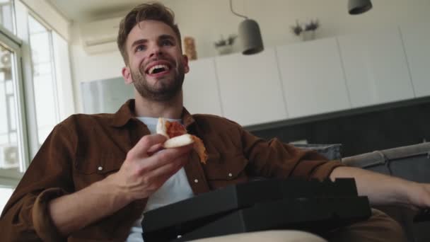 Bel Giovane Uomo Sta Mangiando Pizza Mentre Guarda Seduto Casa — Video Stock