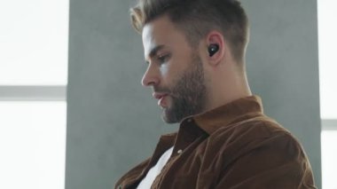 Kulaklıklı çekici bir gencin yakın plan görüntüsü bilgisayarıyla evde oturuyor.