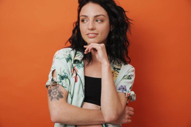 Portakal rengi duvar arkasında izole edilmiş gülümseyen genç bir kadın görüntüsü