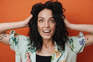 Portakal rengi duvar arkasında izole edilmiş gülümseyen genç bir kadın görüntüsü