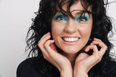 Çekici, gülümseyen esmer bir kadının güzel portresi. Parlak makyajlı, kıvırcık saçlı, beyaz arka planda izole bir kadın.