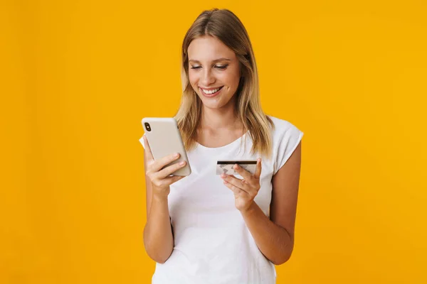 Glada Blond Flicka Med Mobiltelefon Och Kreditkort Isolerad Över Gul — Stockfoto