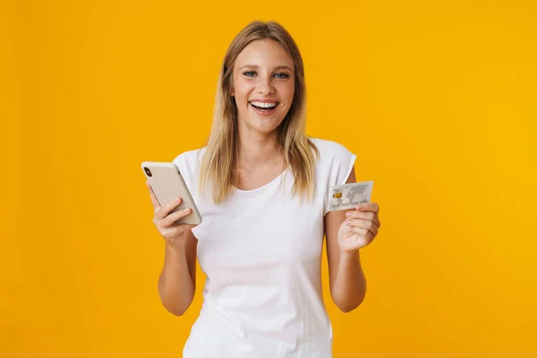 Fröhliches Blondes Mädchen Mit Handy Und Kreditkarte Isoliert Über Gelbem — Stockfoto