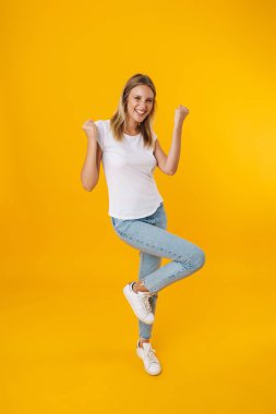 Mutlu güzel kız gülümserken kazanan jest sarı arka planda izole ediliyor.