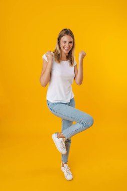 Mutlu güzel kız gülümserken kazanan jest sarı arka planda izole ediliyor.