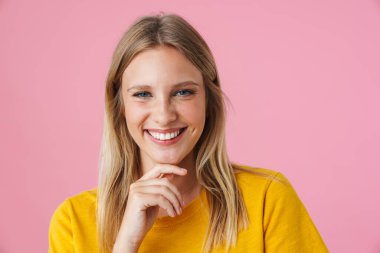 Pembe arka planda izole edilmiş kameraya bakarken gülümseyen güzel kız.