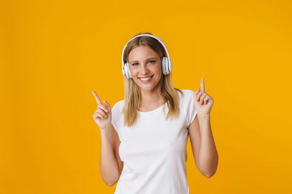 Allegro Ragazza Bionda Cuffie Puntando Dito Verso Alto Isolato Sfondo — Foto Stock