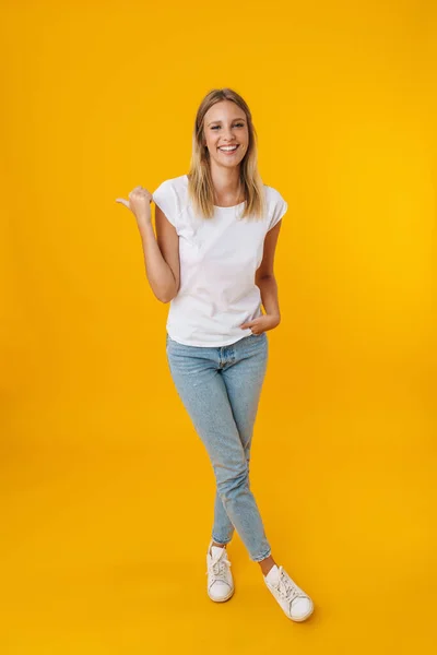 Cheerful Beautiful Girl Smiling While Pointing Finger Aside Isolated Yellow — ストック写真