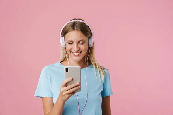 Χαρούμενη Ξανθιά Κοπέλα Στα Ακουστικά Χρησιμοποιώντας Κινητό Τηλέφωνο Απομονώνονται Ροζ — Φωτογραφία Αρχείου