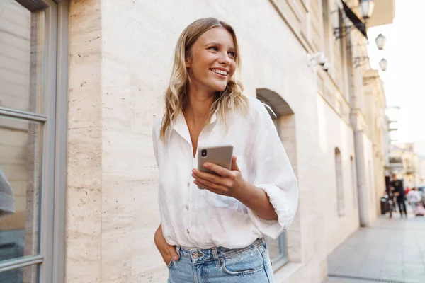 Mulher Feliz Bonita Sorrindo Usando Celular Enquanto Caminha Rua Cidade — Fotografia de Stock