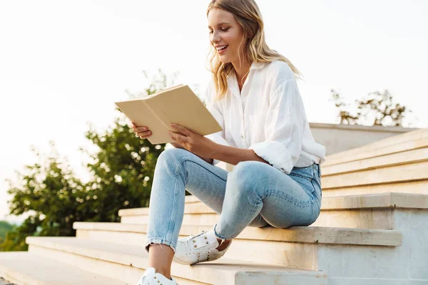 Hermosa Mujer Feliz Sonriendo Leyendo Libro Mientras Está Sentado Escalera —  Fotos de Stock