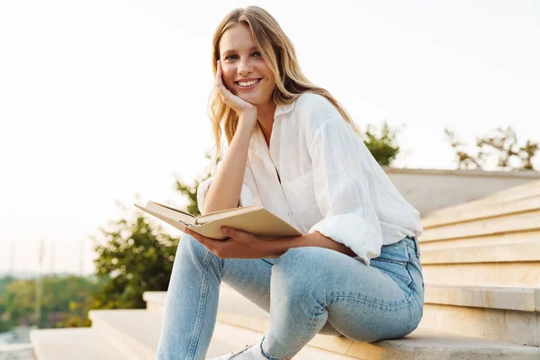 Mulher Feliz Bonita Sorrindo Lendo Livro Enquanto Sentado Escada Livre — Fotografia de Stock