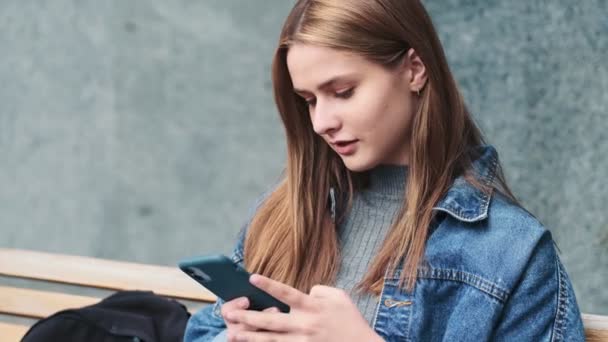 Eine Zufriedene Junge Frau Tippt Telefon Und Sitzt Auf Der — Stockvideo