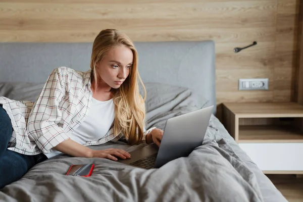 Vacker Blond Fokuserad Kvinna Med Bärbar Dator När Ligger Sängen — Stockfoto