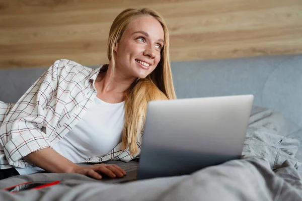 Vacker Blond Leende Kvinna Som Använder Laptop När Ligger Sängen — Stockfoto