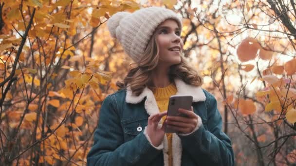 Widok Bliska Uśmiechniętej Młodej Blondynki Używa Smartfona Spacerując Parku Zewnątrz — Wideo stockowe