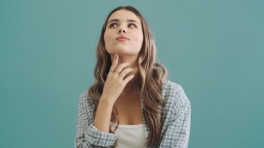 Mutlu bir kadın, mavi arka planda tek başına duran bir şeyin hayalini kuruyor.