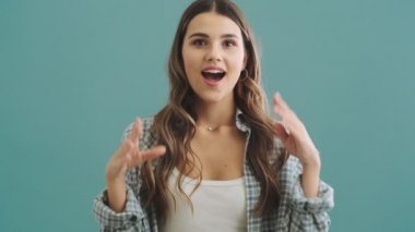 Mutlu, sevimli bir kadın mavi arka planda tek başına ayakta alkışlıyor.