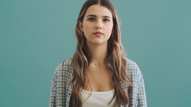 Gülümseyen bir kadın mavi arka planda izole bir şekilde baş parmak hareketi yapıyor.