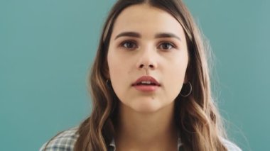 Güzel bir kadının yakın çekim görüntüsü, mavi arka planda tek başına duran gözetleme deliğine bakıyor.