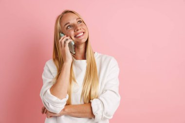 Pembe arka planda izole edilmiş, gülümseyen ve konuşan neşeli güzel kız.