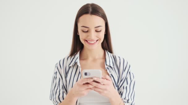Усміхнена Жінка Використовує Свій Смартфон Стоїть Ізольовано Білому Тлі Студії — стокове відео