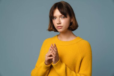 Mavi arka planı düşünen düşünceli çekici bir genç kadın.