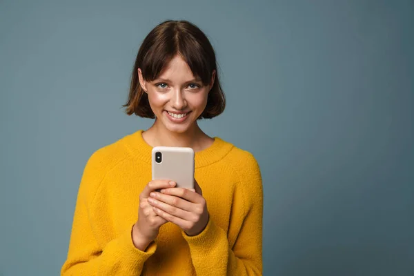 Portret Młodej Uśmiechniętej Nastolatki Trzymającej Telefon Komórkowy Niebieskim Tle — Zdjęcie stockowe