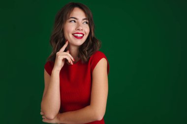 Güzel, mutlu, esmer kız gülümseyen ve yeşil arka planda tek başına bir kenara bakan.