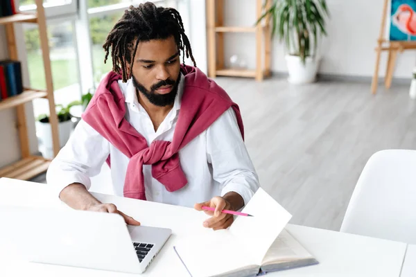Zaměřené Africký Američan Chlap Pracuje Notebookem Knihy Zatímco Sedí Kanceláři — Stock fotografie