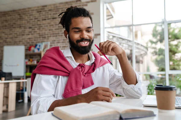 Χαρούμενος Αφροαμερικάνος Ακουστικά Που Δουλεύει Βιβλίο Και Λάπτοπ Ενώ Κάθεται — Φωτογραφία Αρχείου