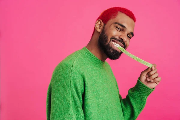 Joyful African American Guy Grimacing While Eating Gummy Isolated Pink — ストック写真
