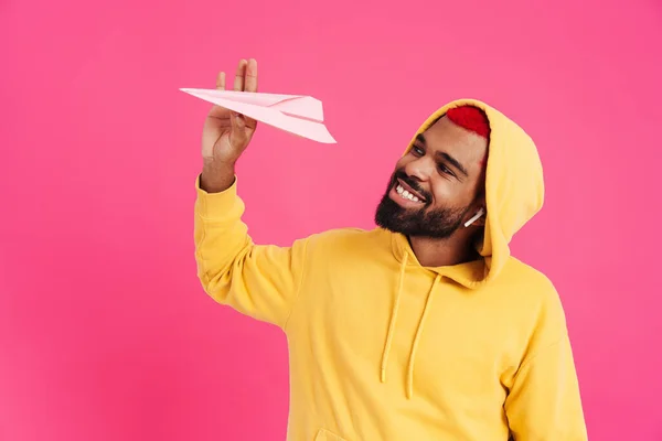 Vreugdevolle Afro Amerikaanse Man Oortelefoons Houden Papieren Vliegtuig Geïsoleerd Roze — Stockfoto