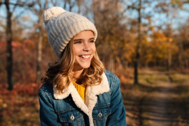 Sonbahar parkında dışarıda yürüyen güzel, mutlu bir kız resmi.