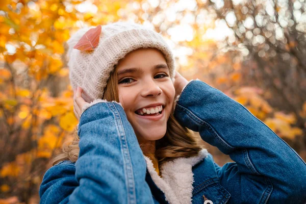 Sonbahar parkında gezen neşeli genç bir kız resmi.