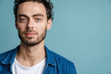 Mavi arka planda izole edilmiş, poz veren ve kameraya bakan yakışıklı adam.