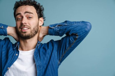 Mavi arka planda izole edilmiş, poz veren ve kameraya bakan yakışıklı adam.