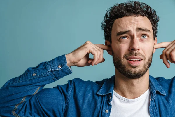 Blank Ongelukkige Man Poseren Pluggen Zijn Oren Geïsoleerd Blauwe Achtergrond — Stockfoto